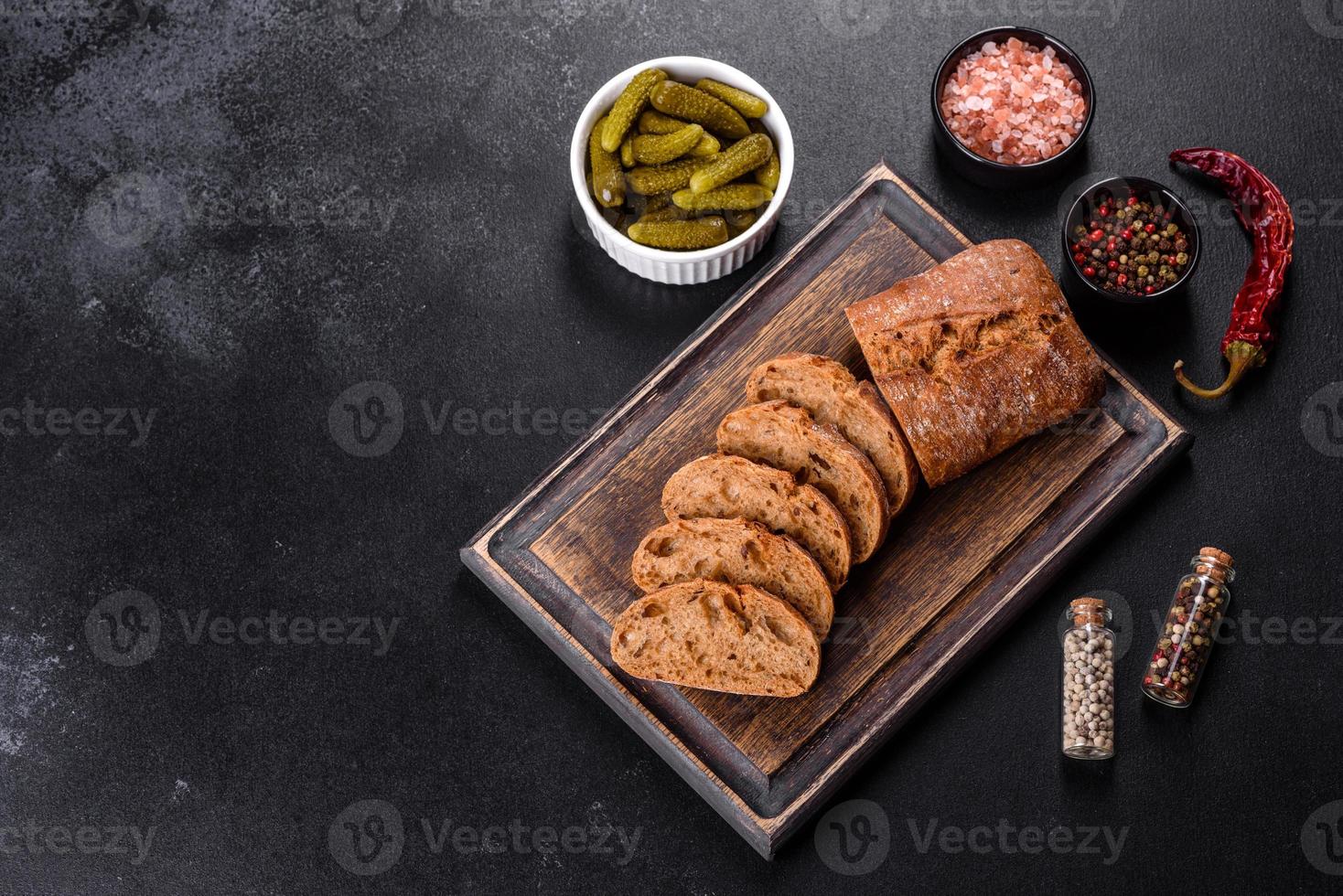 delizioso pane nero fresco affettato con fette su uno sfondo di cemento scuro foto