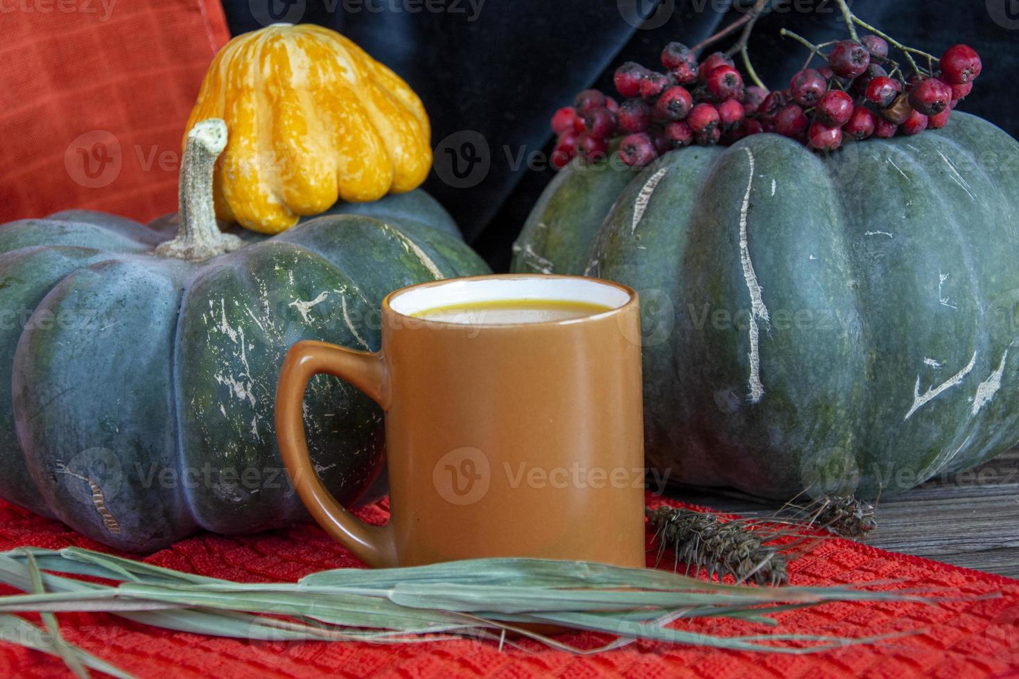 autunno natura morta con zucche. zucche, candele, cereali e una tazza su un tavolo di legno. foto