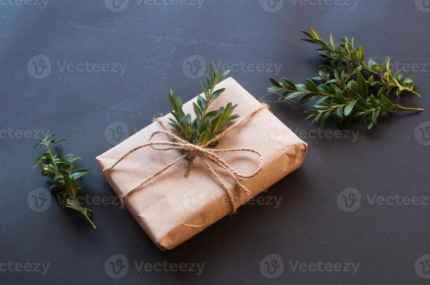 confezione regalo artigianale con nodo naturale con foglie verdi su sfondo nero foto