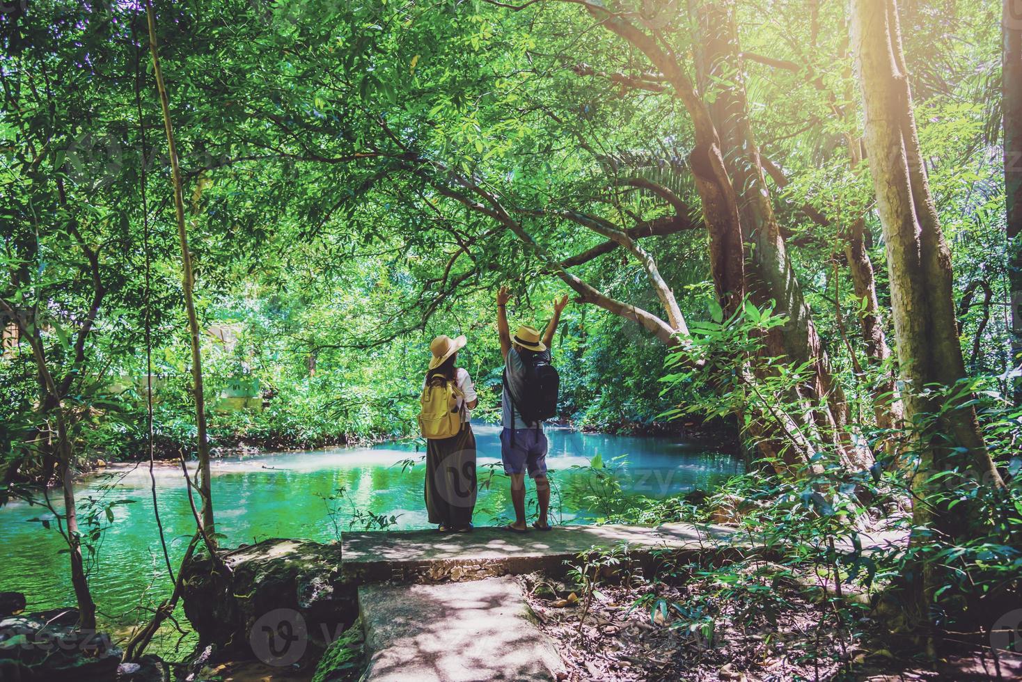 viaggiatori, coppie con zaini da viaggio naturali durante le vacanze. coppie che viaggiano, si rilassano nella giungla verde e si godono il bellissimo laghetto color smeraldo. turismo, escursionismo, studio della natura. foto