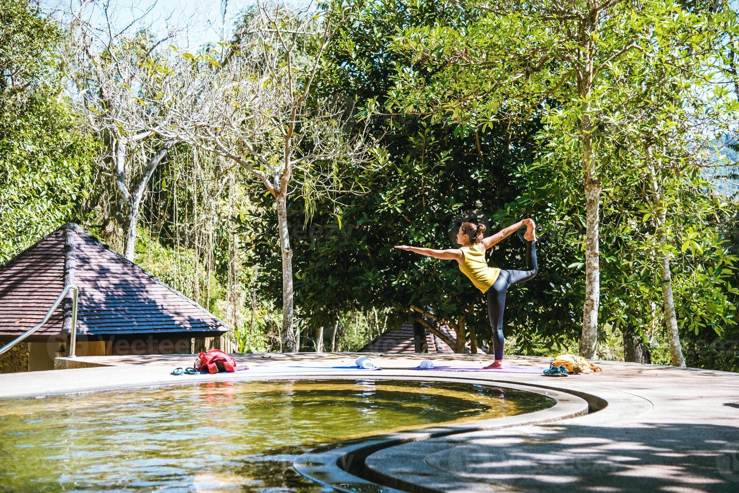 le donne asiatiche si rilassano durante le vacanze. gioca se lo yoga nella sorgente termale in piscina, rilassandoti in un esercizio di postura naturale hot springs.yoga. foto