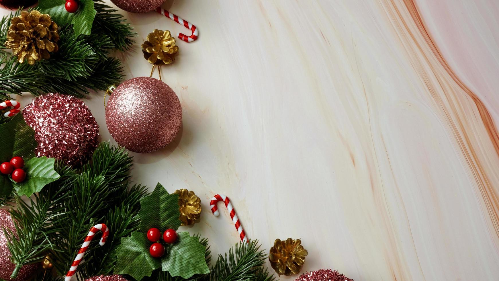 foglie di pino verde, decorazioni natalizie rosa e bastoncini di zucchero su sfondo di marmo morbido, decorazioni natalizie in colore rosa brillante e fantasia. concetto di natale semplice e creativo. foto