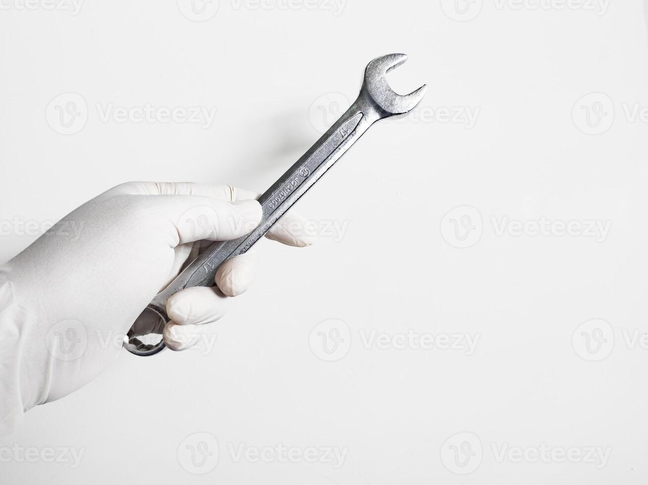 dell'uomo mano con guanti detiene un' chiavi isolato su bianca sfondo. meccanico utensili concetto. foto