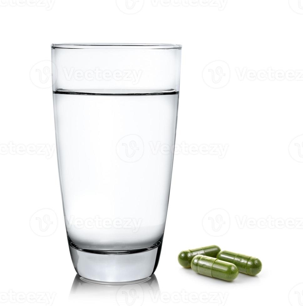 bicchiere d'acqua e pillole di capsule di moringa su sfondo bianco foto
