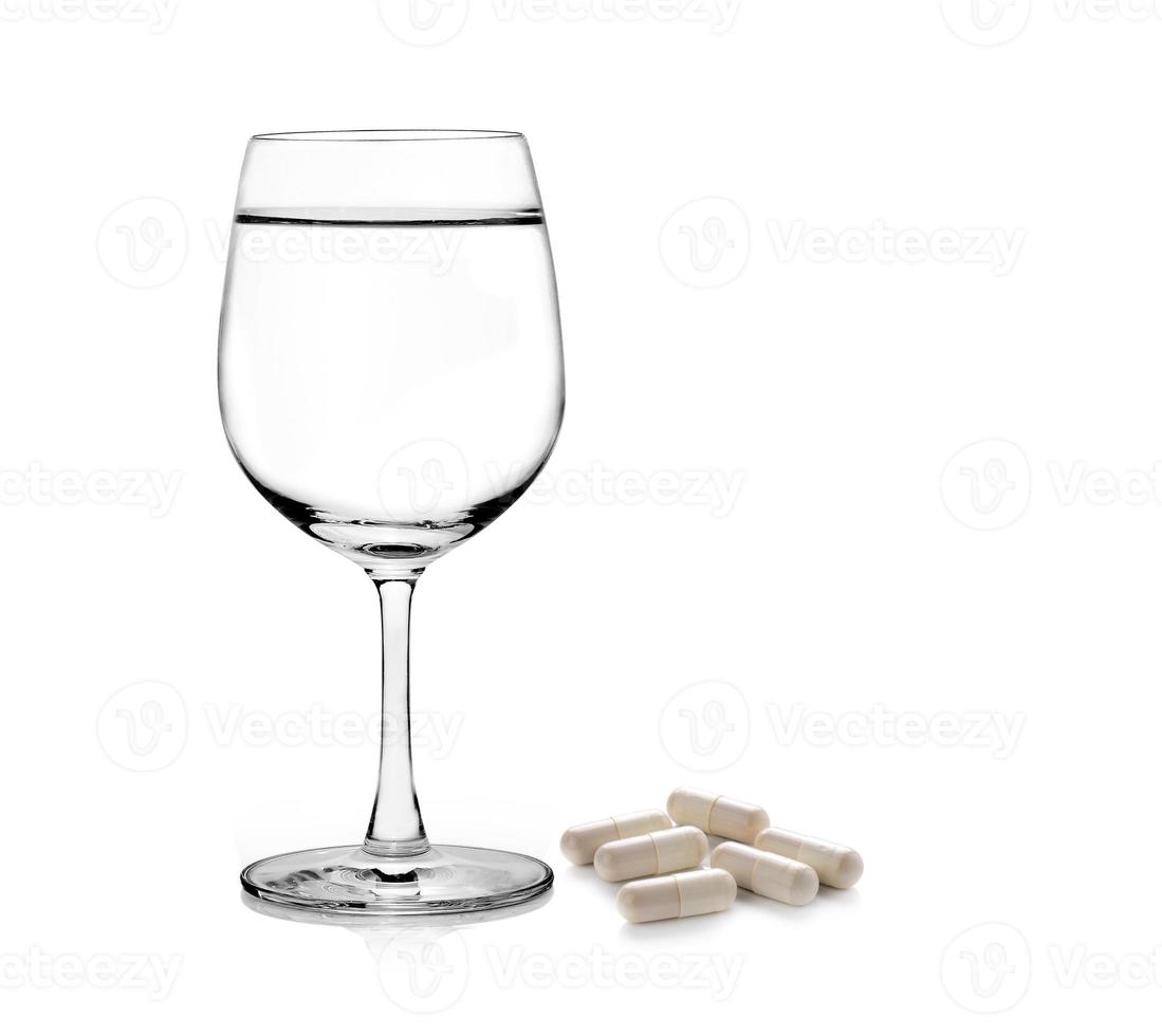 bicchiere d'acqua e pillole capsule isolate su sfondo bianco foto