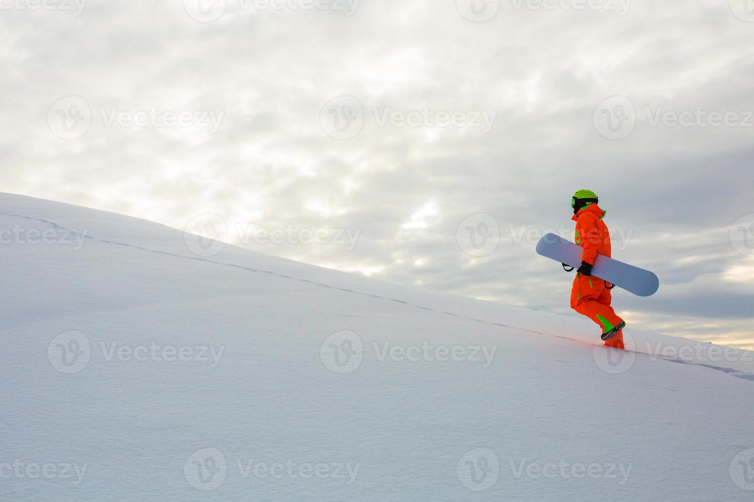 snowboarder che si arrampica in cima alla pista da sci foto