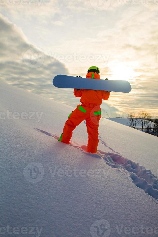 snowboarder che si arrampica in cima alla pista da sci foto