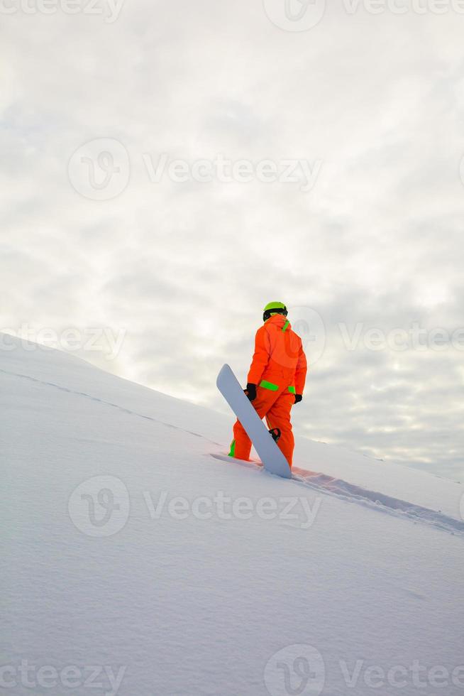 snowboarder che si arrampica in cima alla pista da sci foto