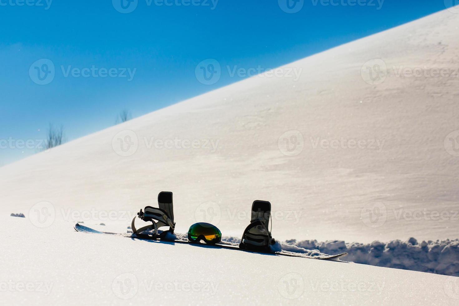 snowboard e occhiali da sci adagiati sulla neve vicino alla pista da freeride foto