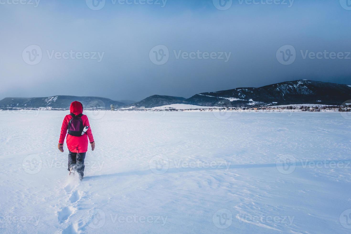 donna che cammina da sola su un lago ghiacciato durante la fredda giornata invernale foto