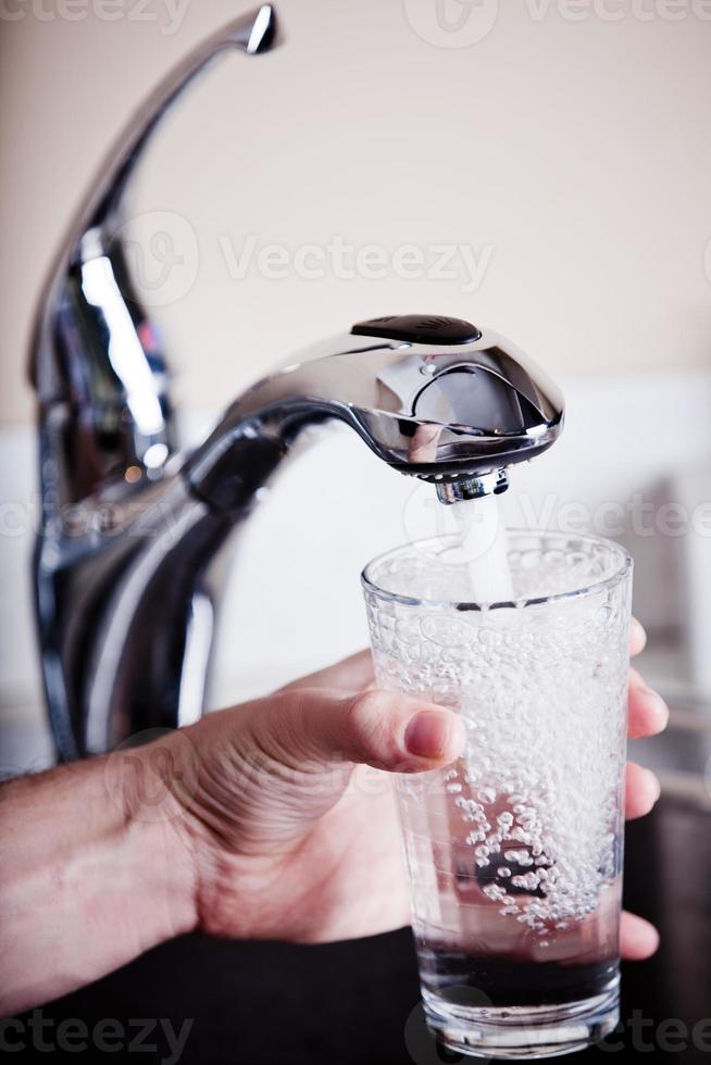 uomo assetato che riempie un grande bicchiere d'acqua foto