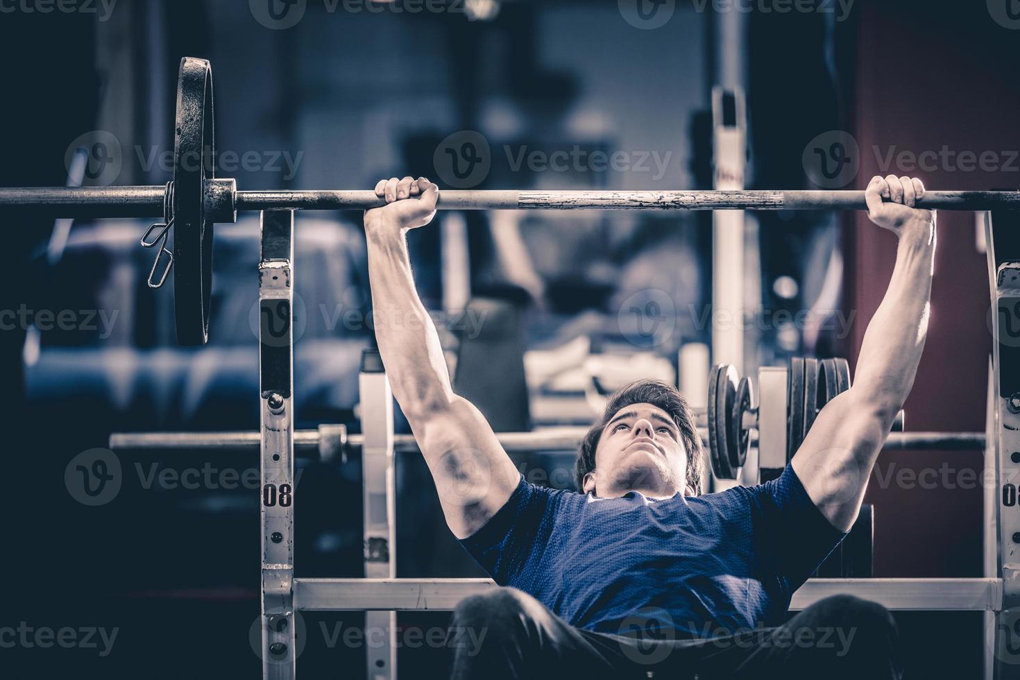 uomo che fa panca in palestra foto