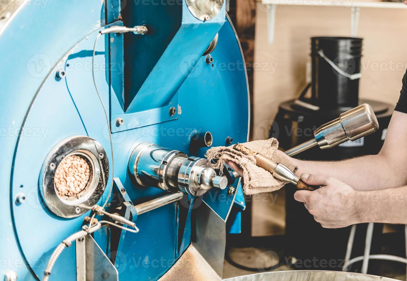 lavoratore del raccolto che controlla i chicchi nella torrefazione del caffè foto