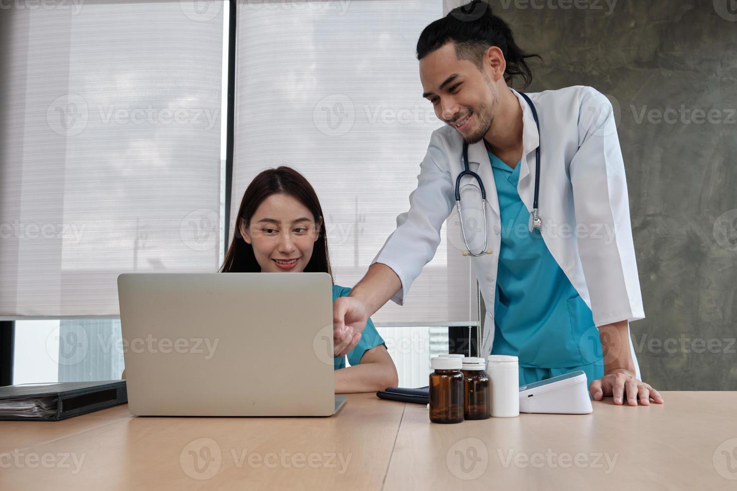 partner del team sanitario. due giovani medici di etnia asiatica in uniforme sono colleghi che discutono di farmaci nell'ufficio della clinica dell'ospedale. le persone specializzate sono esperti e professionisti. foto