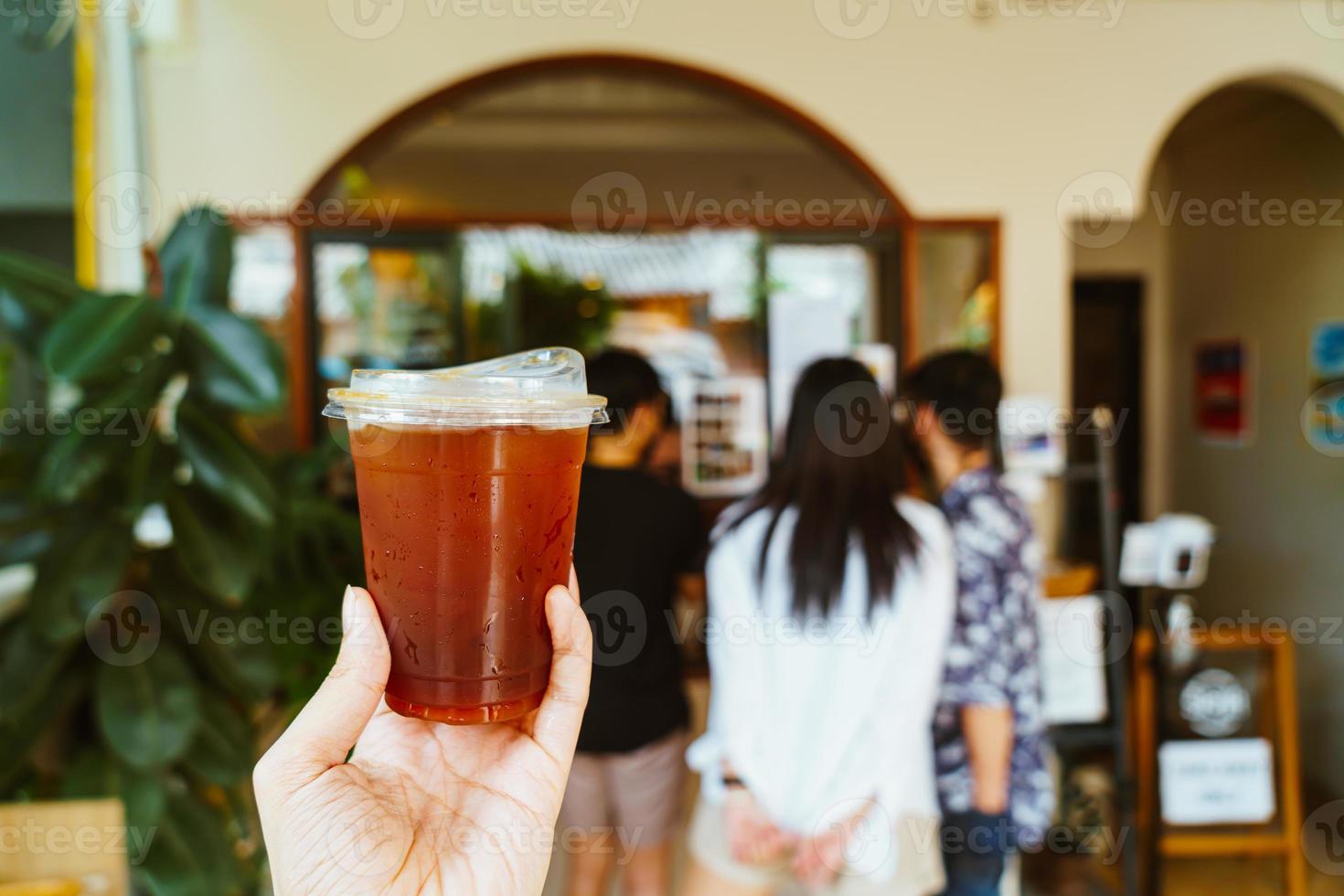 mano che tiene un bicchiere di caffè americano ghiacciato foto