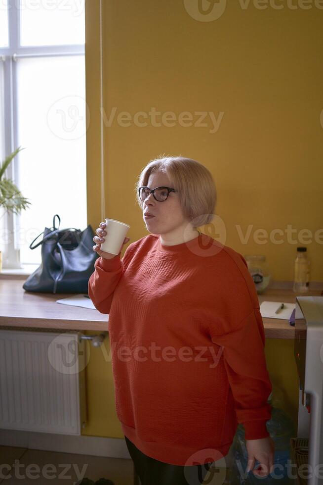 Disabilitato persona potabile caffè nel il ufficio cucina foto