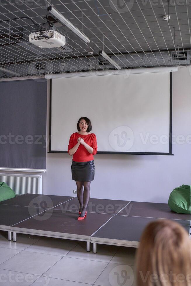 donna dando emotivo discorso su palcoscenico, prestazione sala nel ufficio foto