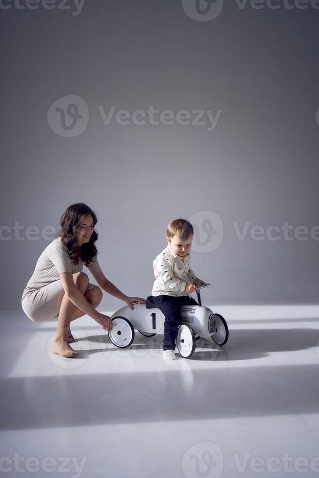 emotivo madre giocando con sua poco figlio e il suo giocattolo auto foto