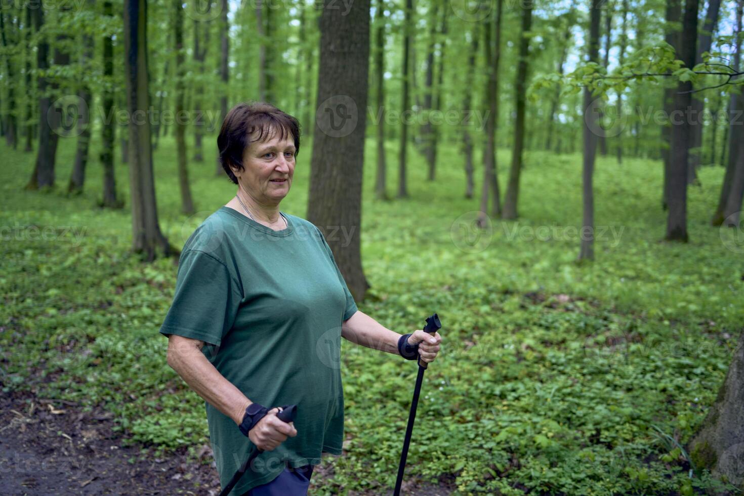 anziano donna è impegnato nel nordico a piedi con bastoni nel il primavera foresta foto