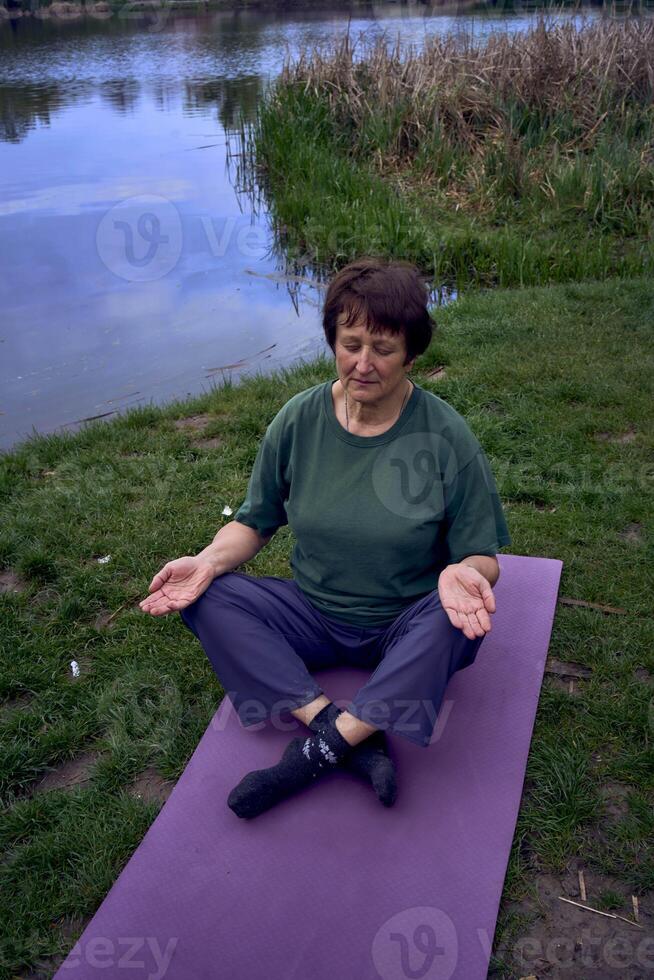 un vecchio donna Meditare nel il mattina su il banca di il fiume, è venuto a partire dal casa di bicicletta foto