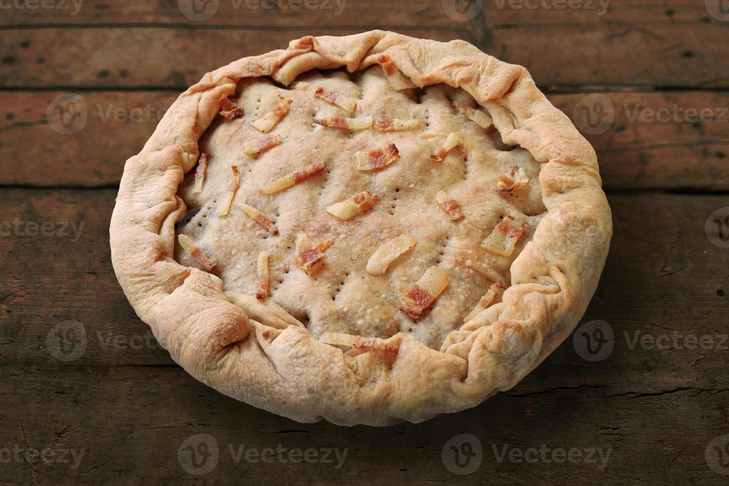 torta salata intera con pancetta su tavola di legno grezzo foto