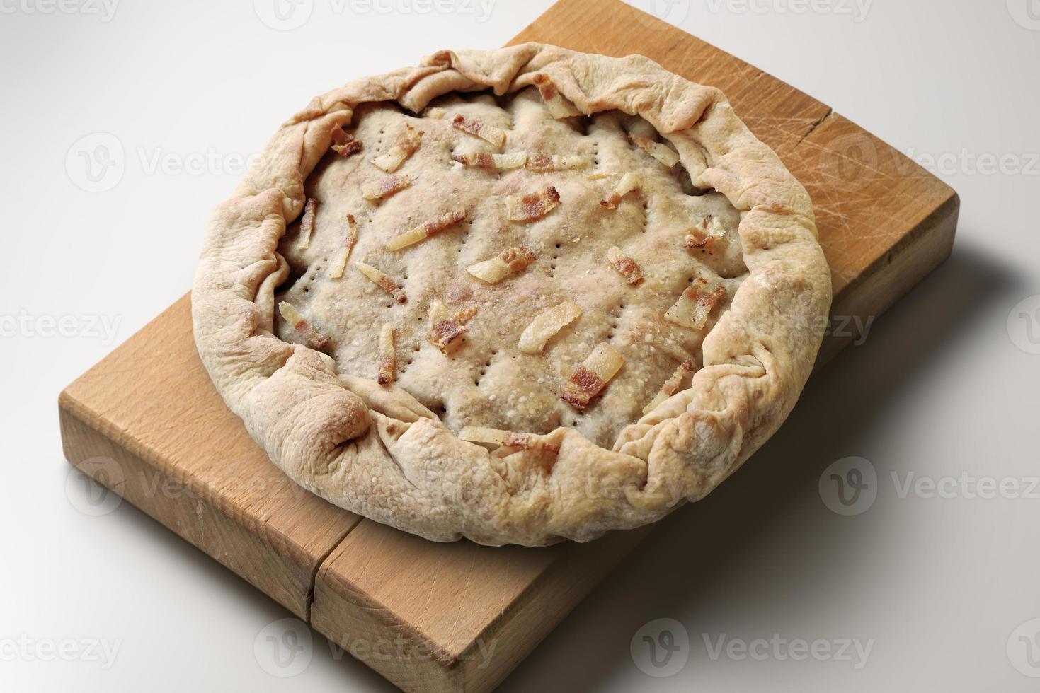 torta salata con pancetta su tagliere in legno foto