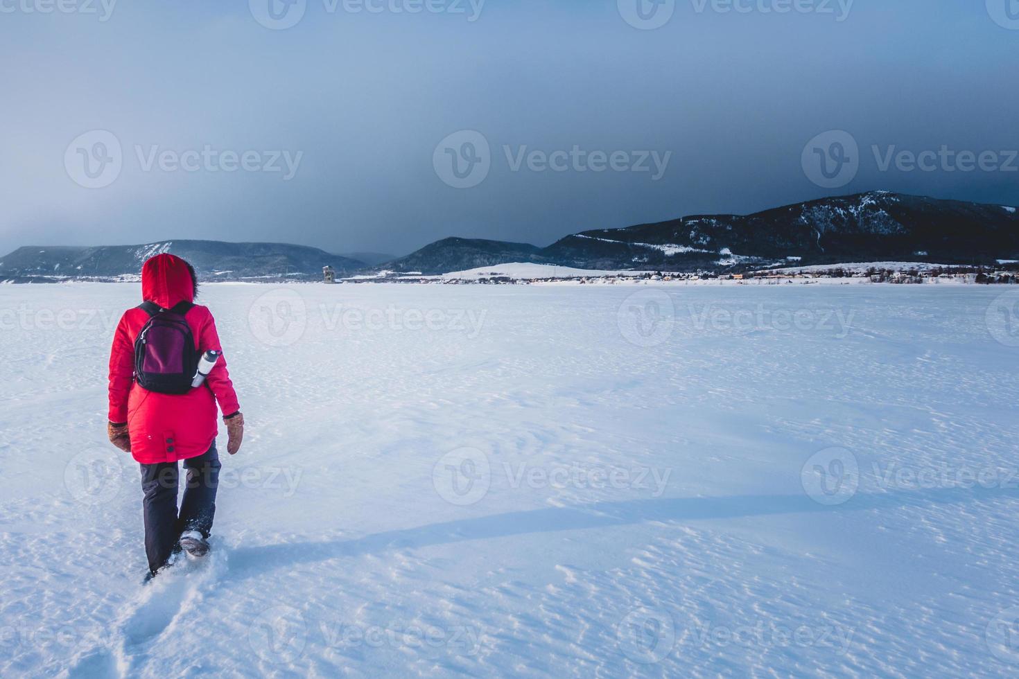 donna che cammina da sola su un lago ghiacciato durante la fredda giornata invernale foto