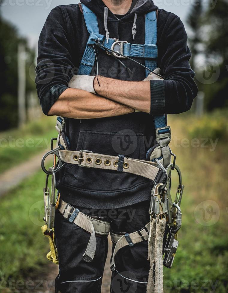 tecnico in uniforme con imbracatura in piedi con le braccia incrociate. foto