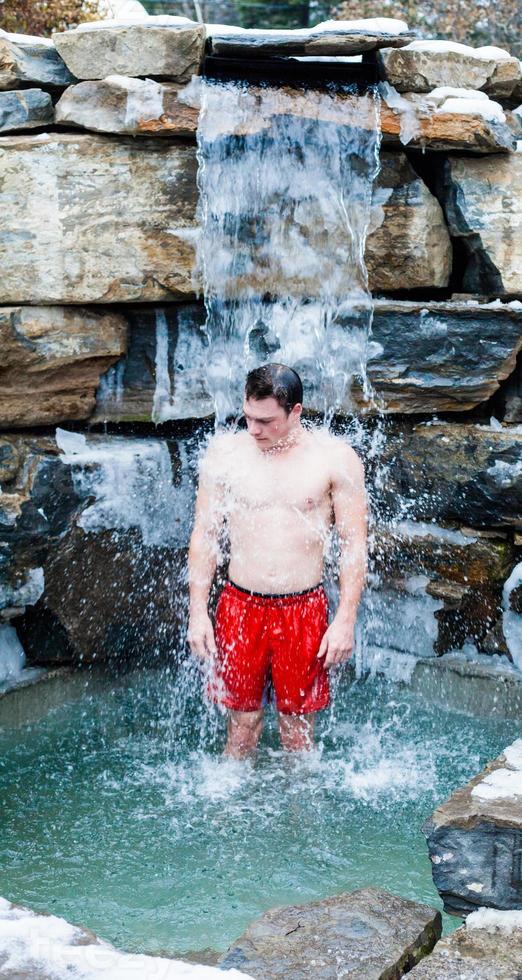 uomo sotto la cascata termale nordica con acqua fredda foto
