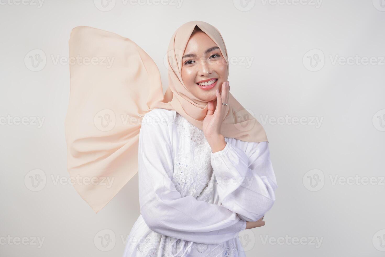 elegante giovane asiatico musulmano donna indossare bianca vestito con hijab agitando nel il vento, modellazione posa su bianca sfondo foto