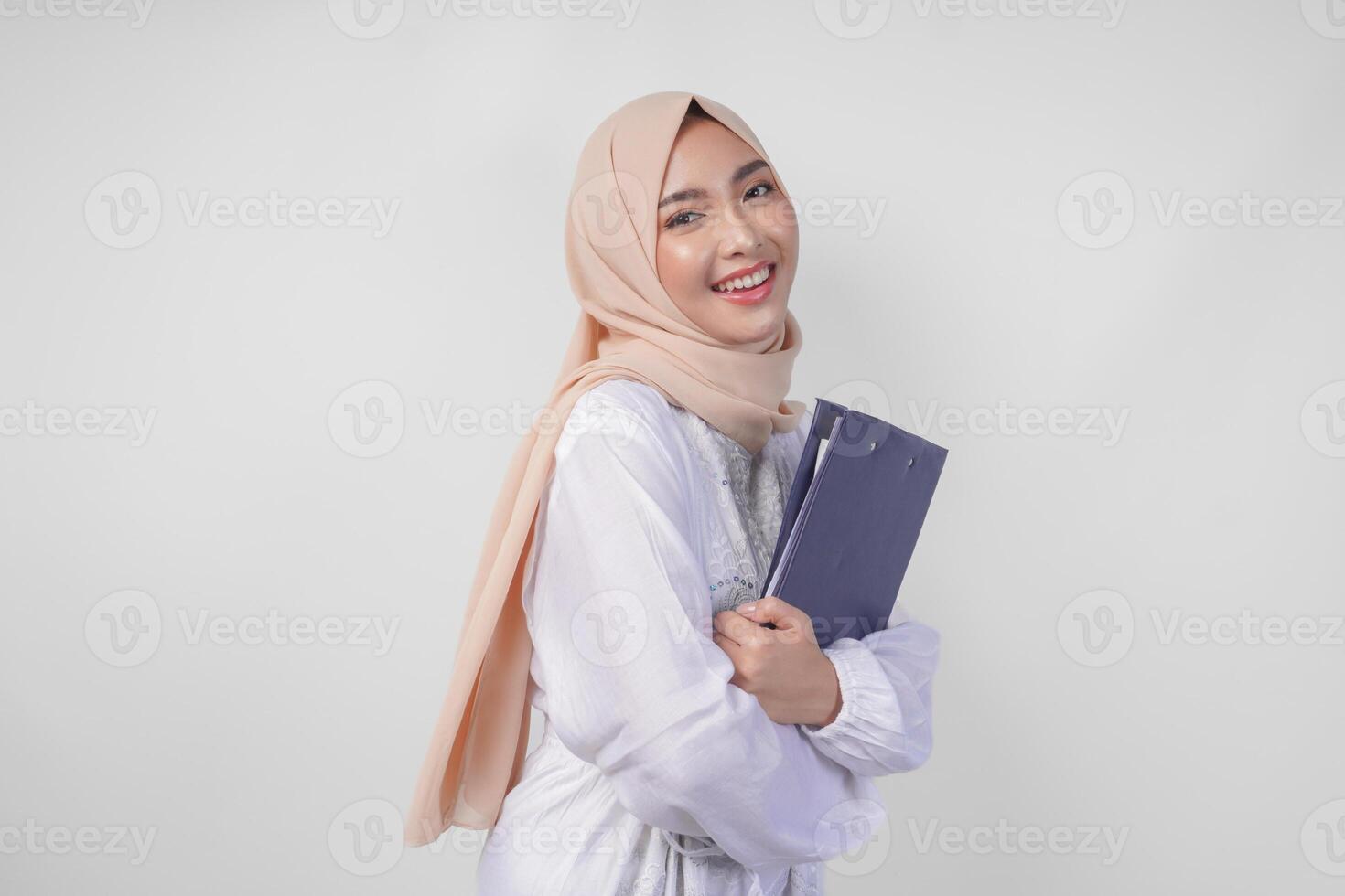 sorridente giovane asiatico musulmano donna indossare bianca vestito e hijab Tenere un' documento, isolato di bianca sfondo. Ramadan e eid mubarak concetto foto