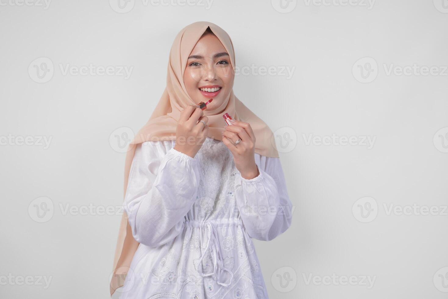 bellissimo giovane asiatico musulmano donna indossare bianca vestito e hijab mettendo su trucco l'applicazione rossetto. moda e cosmetici bellezza concetto foto