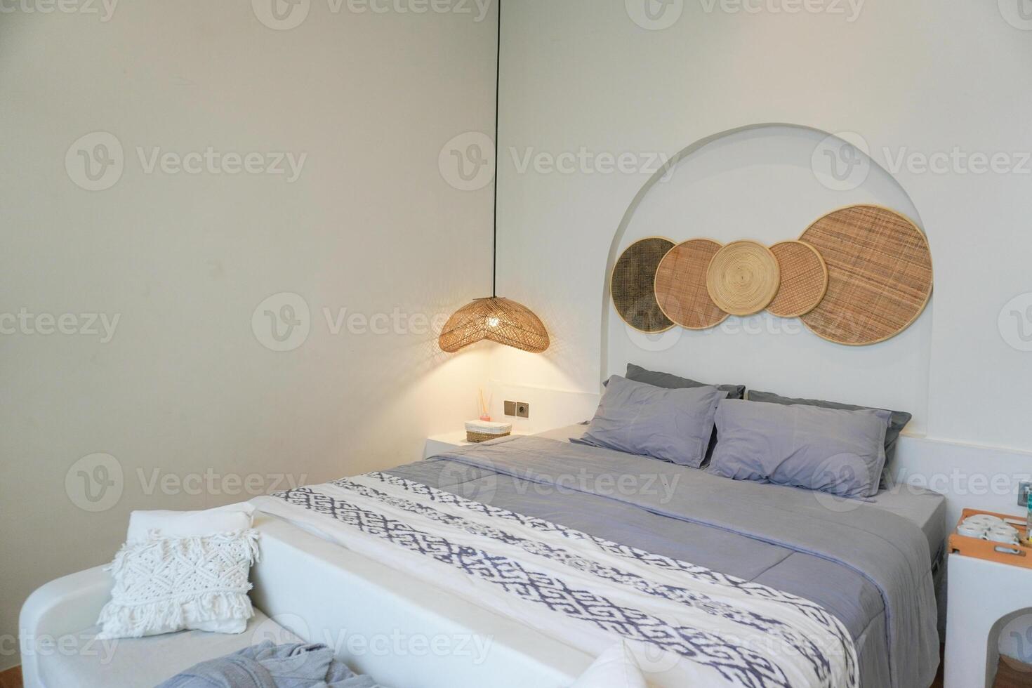 lussuoso villa Camera da letto con confortevole re dimensione letto e grigio fogli, malacca ornamenti su leggero grigio parete. concetto per interno, architettura e stile di vita. foto