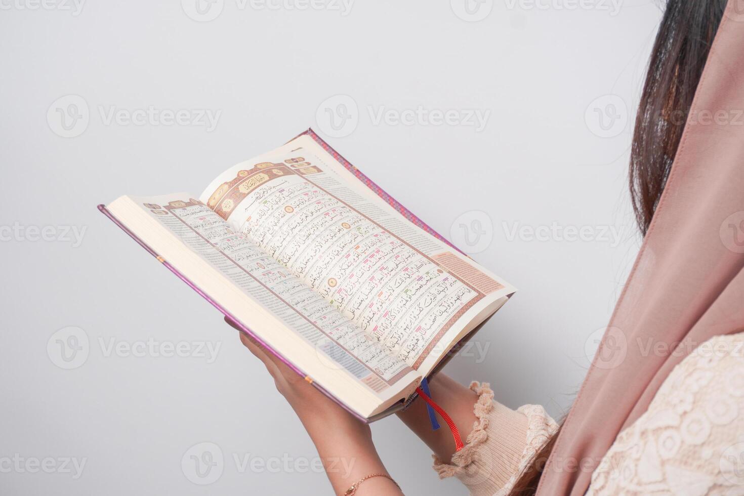 vicino su ritratto di asiatico musulmano donna nel foulard velo hijab Tenere e lettura al Corano al di sopra di isolato bianca sfondo. Ramadan e eid mubarak concetto. foto