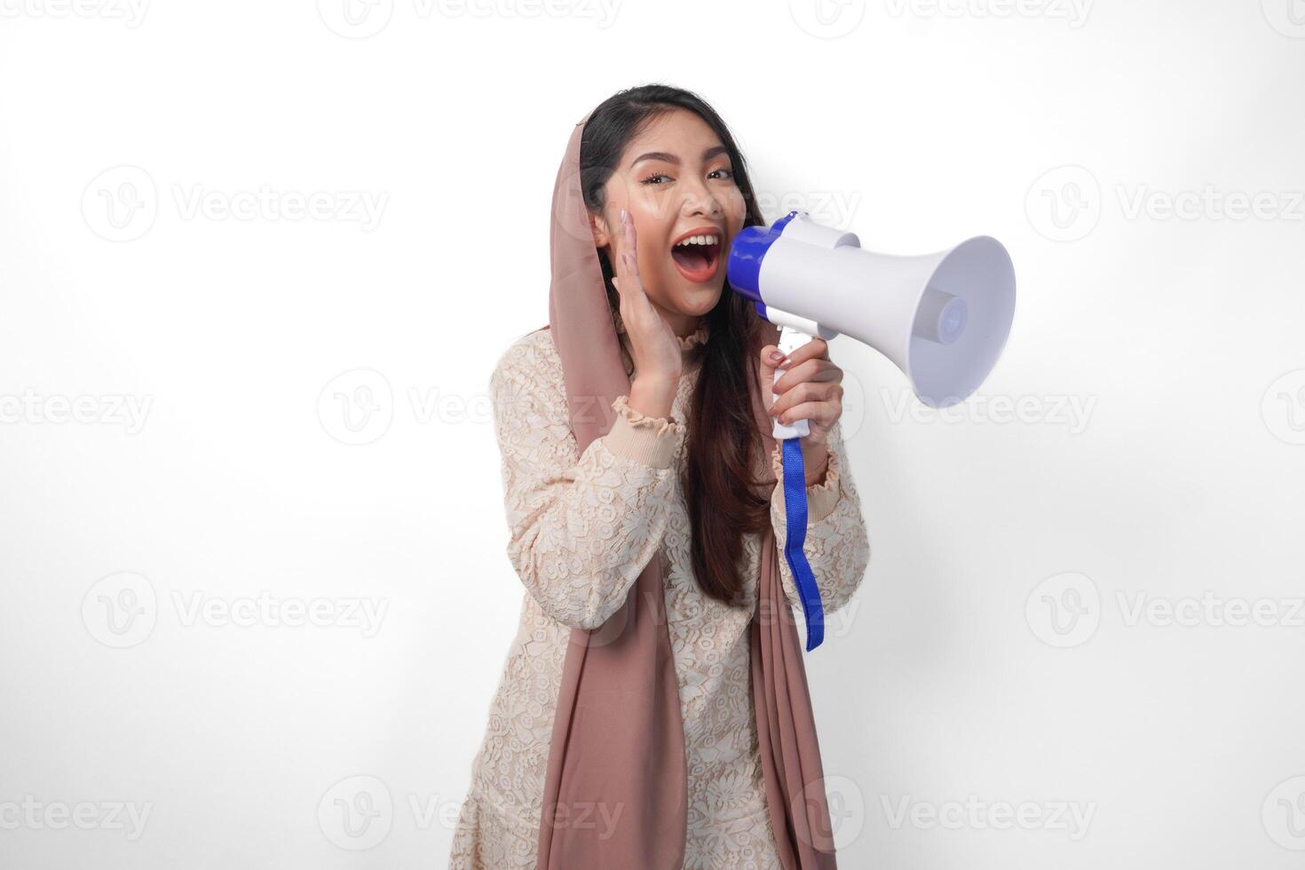vivace giovane asiatico musulmano donna indossare foulard velo hijab urlando a megafono, isolato su bianca sfondo studio. Ramadan e eid mubarak concetto. foto