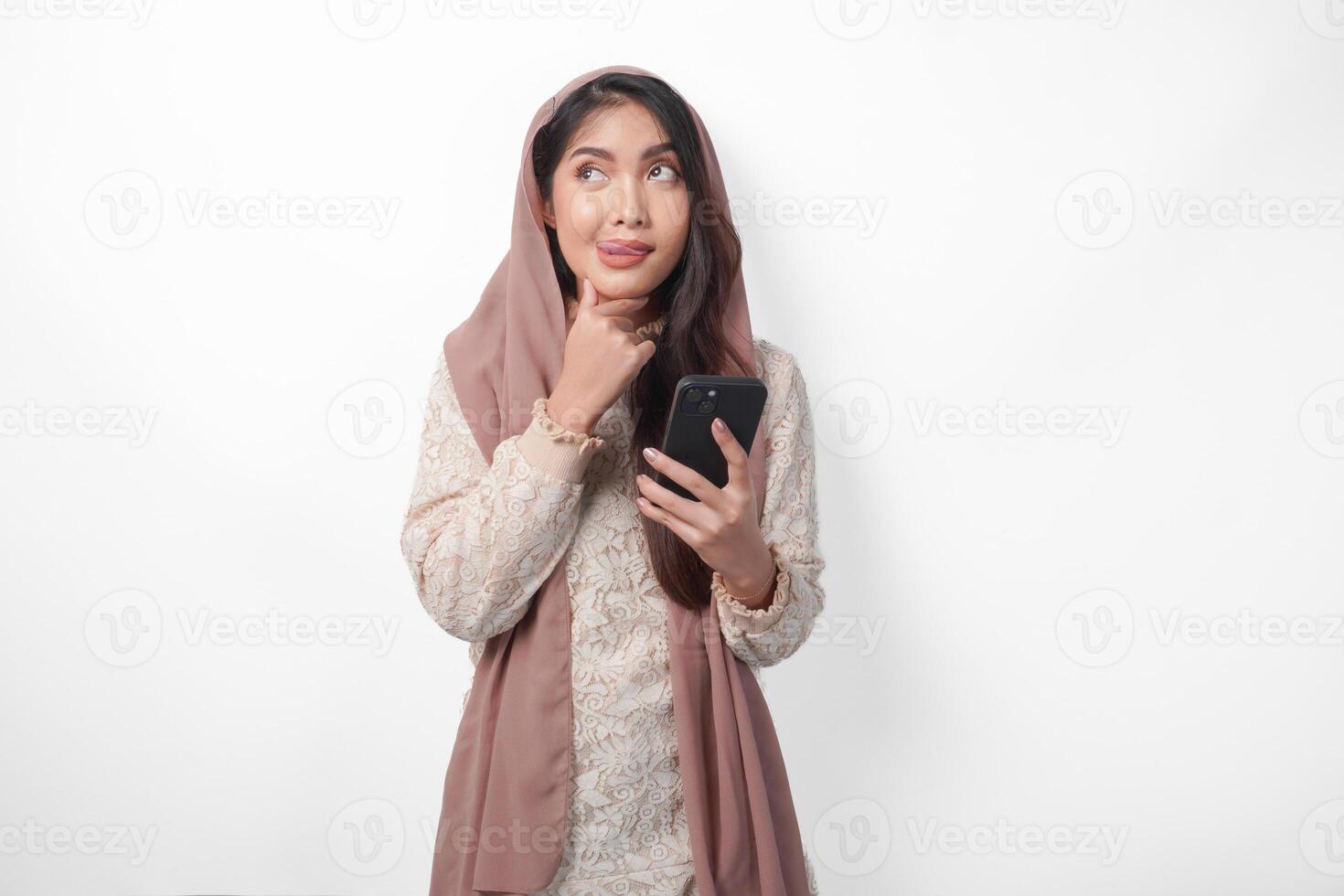 Affamato asiatico musulmano donna nel velo hijab pensiero che cosa per mangiare dopo digiuno mentre utilizzando un' smartphone per ordine Alimenti. Ramadan concetto foto