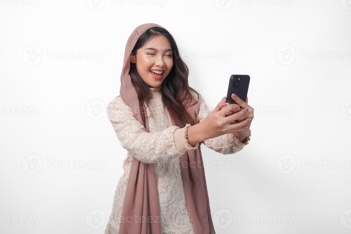 ritratto di giovane asiatico musulmano donna nel velo hijab sorridente allegramente mentre Tenere e utilizzando un' smartphone. Ramadan e eid mubarak concetto foto