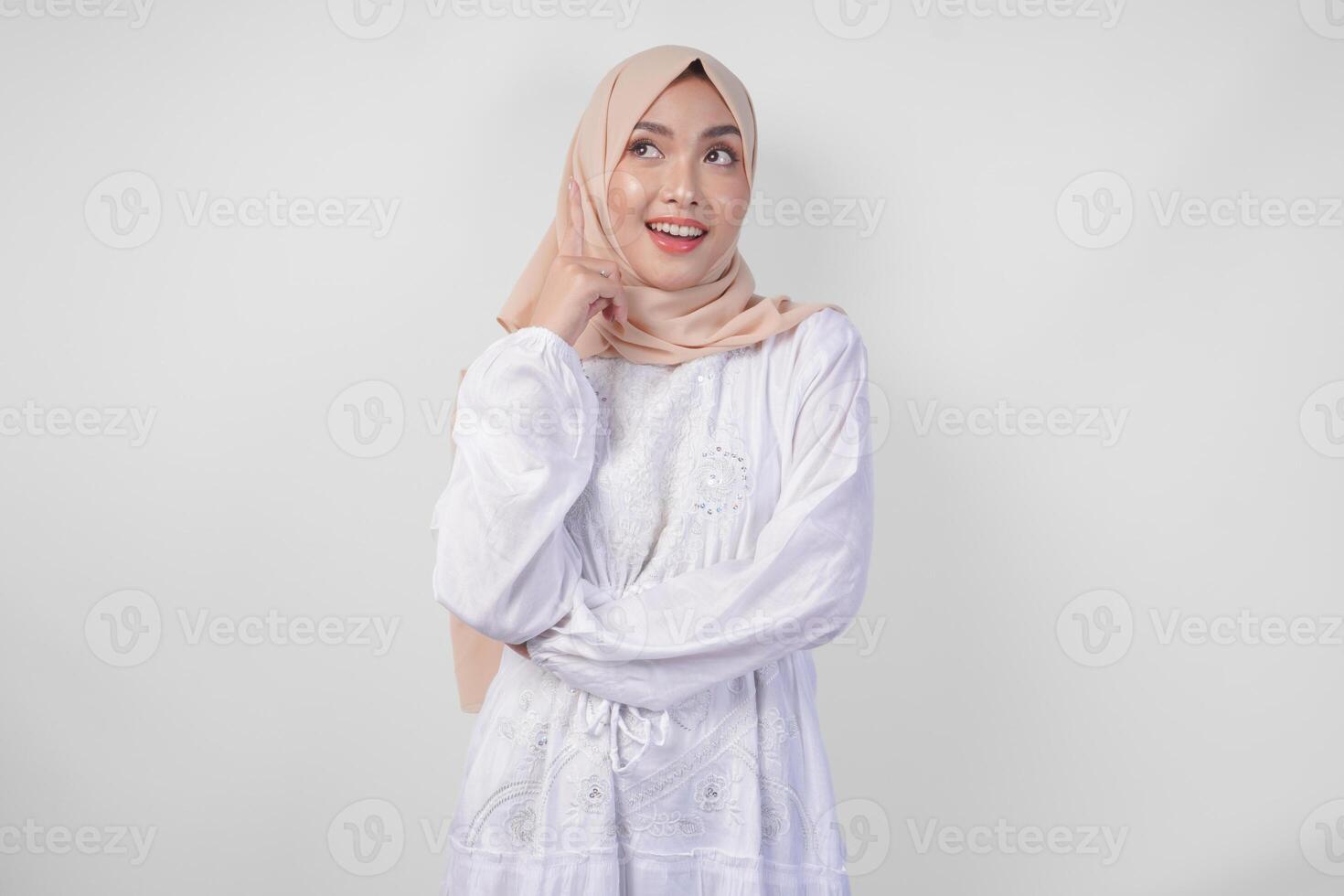 riflessivo giovane asiatico musulmano donna indossare bianca vestito e hijab pensiero e scoperta idea con contento espressione, isolato su bianca sfondo foto