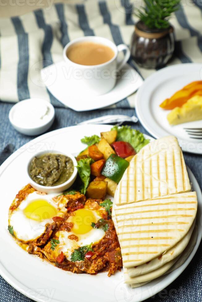 Shakshuka con verdura insalata includere pomodoro, Patata, lattuga foglia e carota con Tè, caffè, e dolce melone servito su cibo tavolo superiore Visualizza salutare prima colazione foto