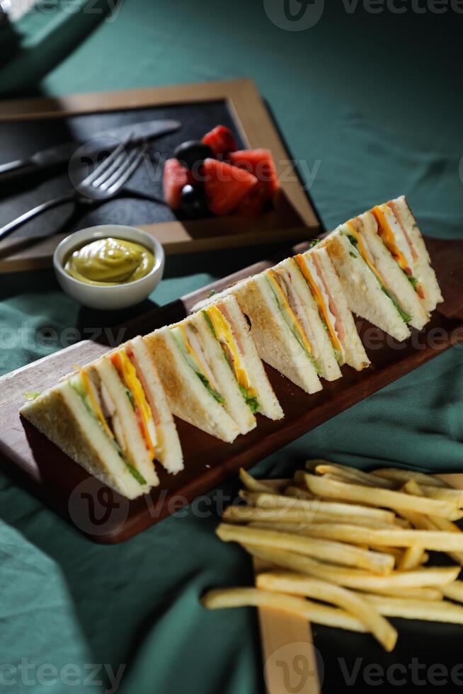 assortito club Sandwich isolato su di legno con Maionese tuffo e francese patatine fritte secchio tavola lato Visualizza di italiano veloce cibo su sfondo foto