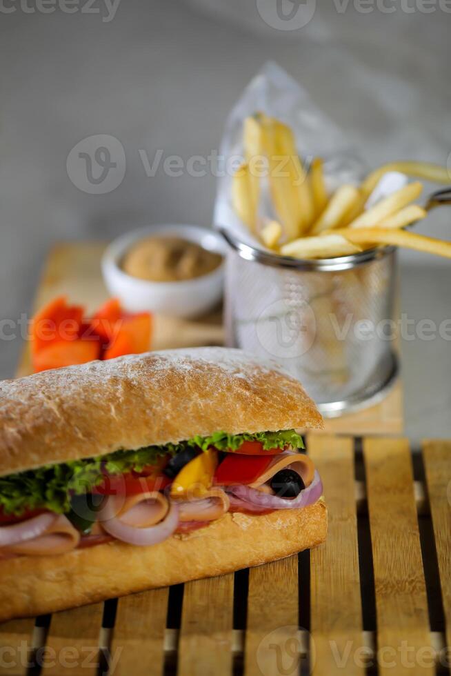 Ciabatta affumicato prosciutto Sandwich isolato su di legno con Maionese tuffo e francese patatine fritte secchio tavola lato Visualizza di italiano veloce cibo su grigio sfondo foto