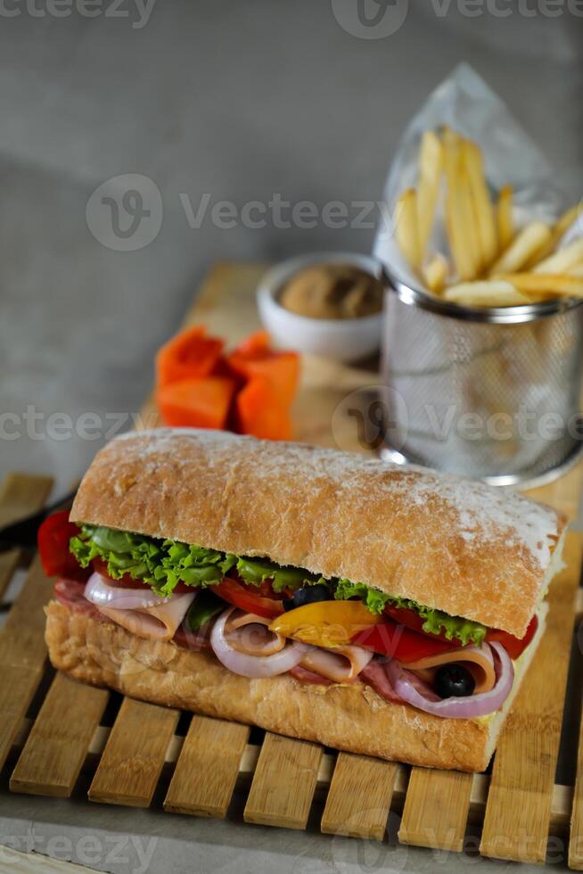 Ciabatta affumicato prosciutto Sandwich isolato su di legno con Maionese tuffo e francese patatine fritte secchio tavola lato Visualizza di italiano veloce cibo su grigio sfondo foto