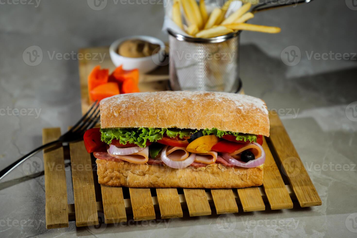 Ciabatta affumicato prosciutto Sandwich isolato su di legno con Maionese tuffo e francese patatine fritte secchio tavola lato Visualizza di italiano veloce cibo su grigio sfondo foto