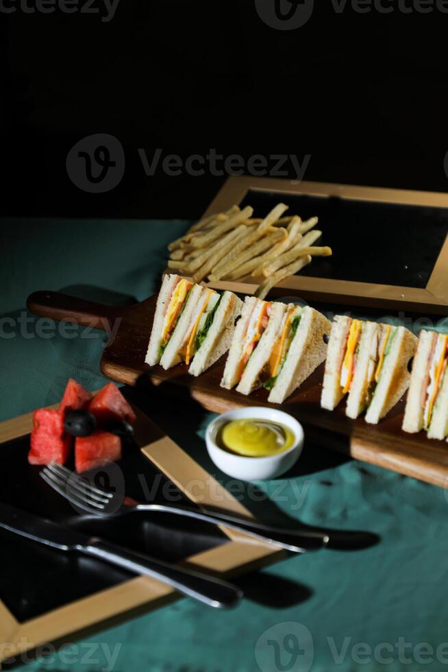 assortito club Sandwich isolato su di legno con Maionese tuffo e francese patatine fritte secchio tavola lato Visualizza di italiano veloce cibo su sfondo foto