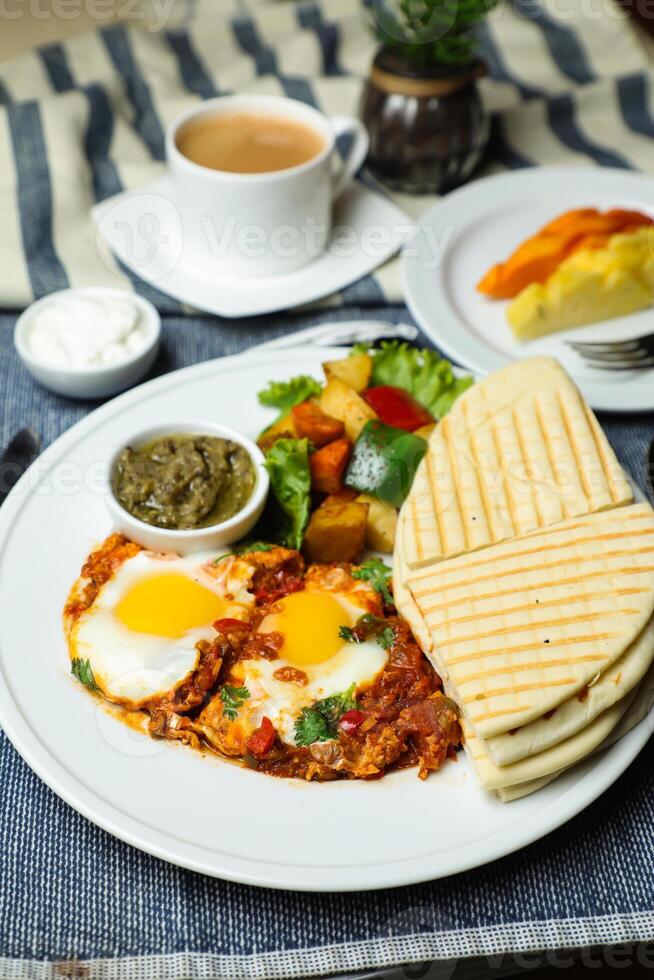 Shakshuka con verdura insalata includere pomodoro, Patata, lattuga foglia e carota con Tè, caffè, e dolce melone servito su cibo tavolo superiore Visualizza salutare prima colazione foto