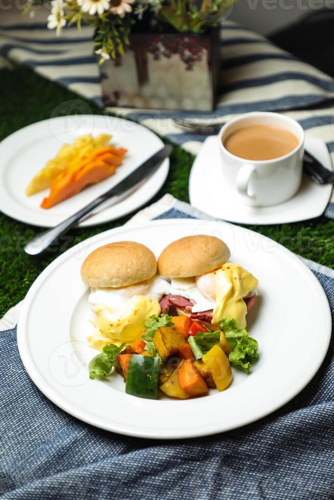 uovo benedetto cursore con verdura insalata includere pomodoro, Patata, lattuga foglia e carota con Tè, caffè, e dolce melone servito su cibo tavolo superiore Visualizza salutare inglese prima colazione foto