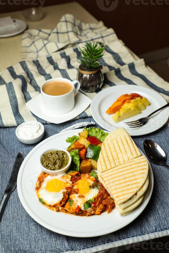 Shakshuka con verdura insalata includere pomodoro, Patata, lattuga foglia e carota con Tè, caffè, e dolce melone servito su cibo tavolo superiore Visualizza salutare prima colazione foto