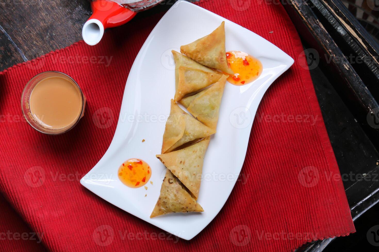 samosa, sambosa, con salsa, tè e teiera servito nel piatto isolato su rosso stuoia superiore Visualizza su tavolo Arabo cibo foto