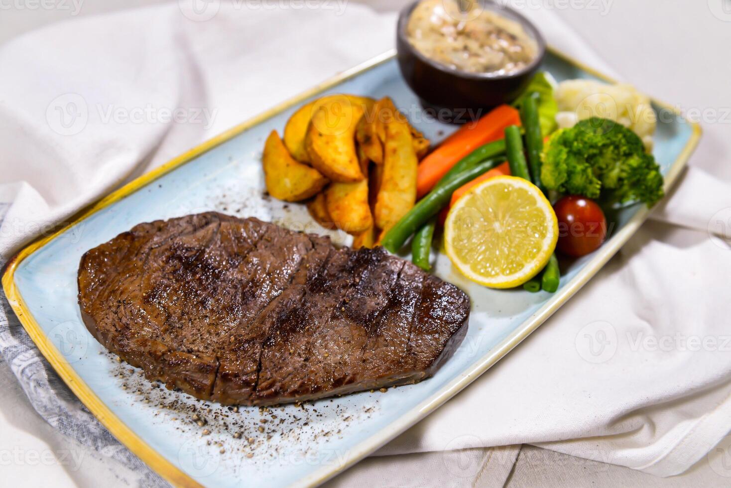 Manzo filetto bistecca con fritte verdure, insalata, Limone e tuffo servito nel piatto isolato su cibo tavolo superiore Visualizza di mezzo est spezie foto