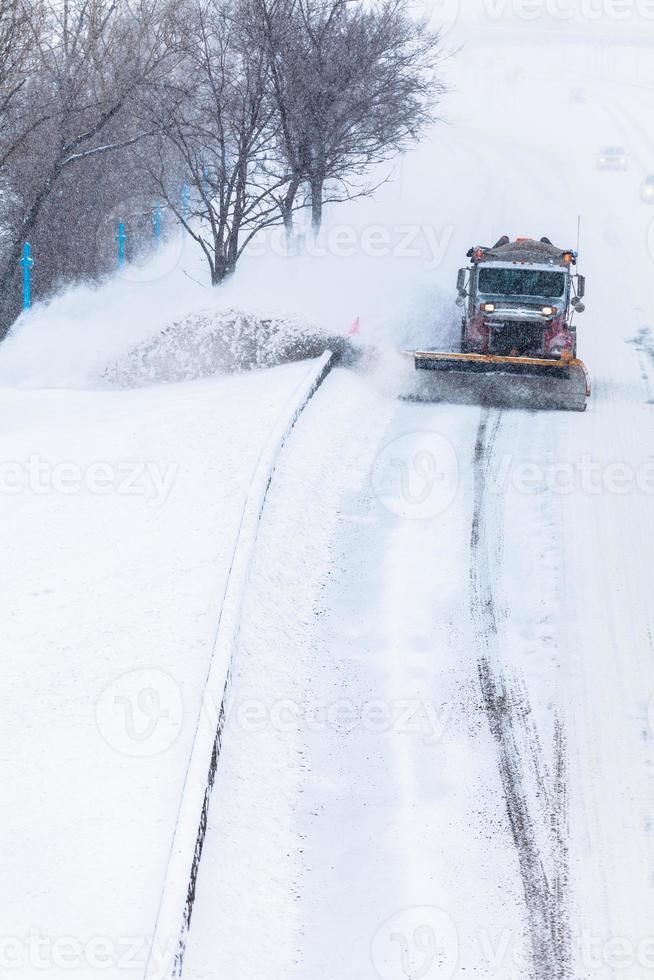 spazzaneve che rimuove la neve dall'autostrada durante una tempesta di neve foto